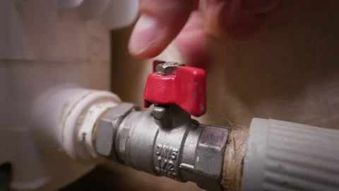Hand Turning Red Lever to Close Metal Ball Valve on Water Heating Pipe Stock Footage 339212254