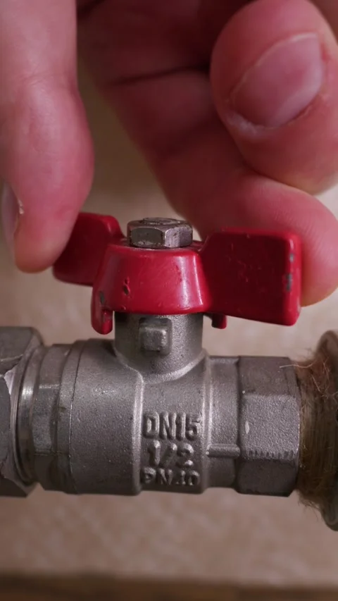 Hand Turning Red Valve to Shut Off Water Flow on Heating Metal Pipe Stock Footage 339213894