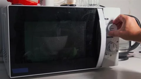 Hand turning rotary control on microwave oven, selecting heating mode and time Stock Footage 333649633