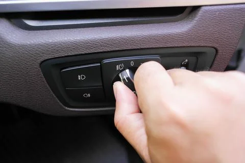 A hand turning the rotary headlight control switch Stock Photos