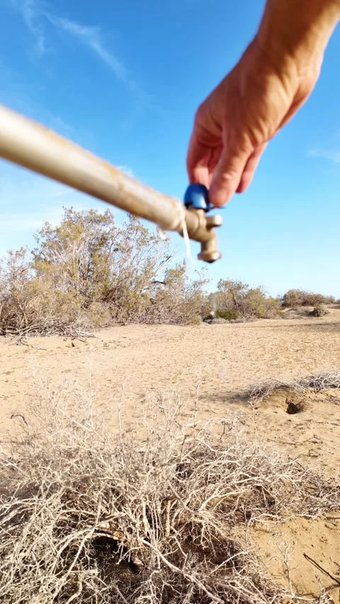 Hand turning off a single leaky faucet in a barren desert Vídeos de archivo 329556589