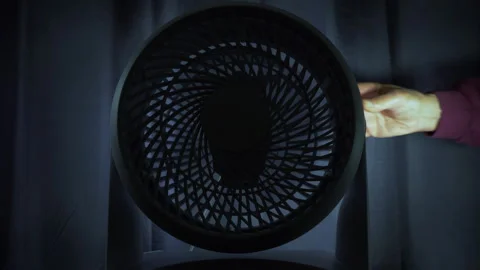 A hand turning off a small cooling fan in a darkened room. Vídeos de archivo 249257185