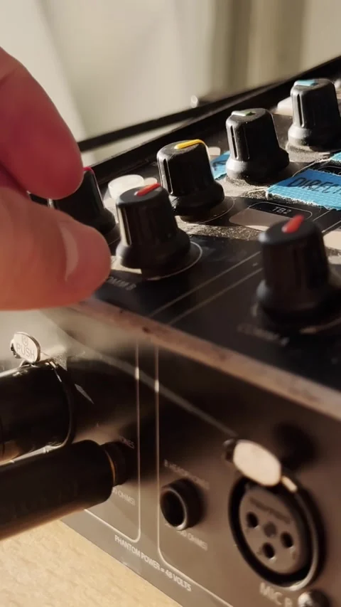 Hand turning a volume knob down on an audio intercom unit with XLR sockets and Stockbeeldmateriaal 336839992
