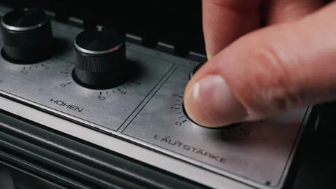 Hand Turning Volume Knob on Retro Audio Amplifier in Extreme Close Up Stockbeeldmateriaal 333818637
