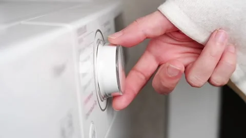 Hand turning washing machine knob to select washing cycle Stock Footage 304364698