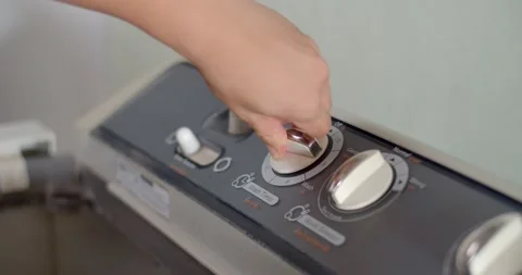 The hand is turning the washing machine timer by turning it to 15 minutes. Stock Footage 223901536