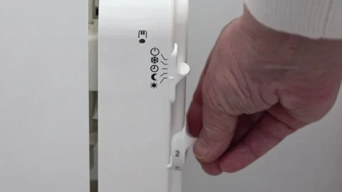 A hand turns on and increases the heating level of a radiator in a room in a  Video stock 328996177