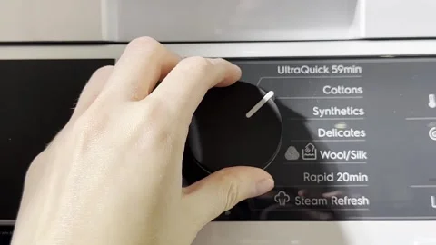 A hand turns the control knob on a washing machine, selecting a wash progra.. Stock Footage 321967501