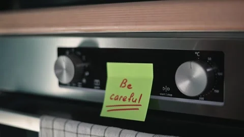 A hand turns the dial of an oven while a note is visible on the appliance. The Stock Footage 339096720