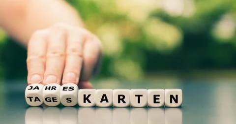Hand turns dice and changes the German word "Tageskarten" ("day tickets") to Stock Photos