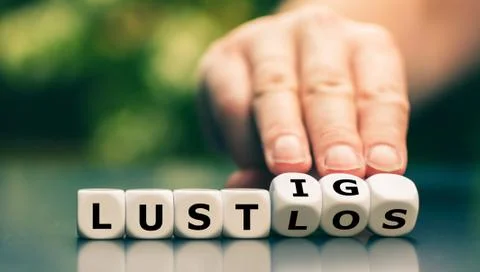 Hand turns dice and changes the German word "lustlos" ("listless") to "lustig Stock Photos