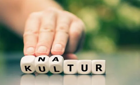 Hand turns dice and changes the German word "Kultur" ("culture") to "Natur" ( Stock Photos