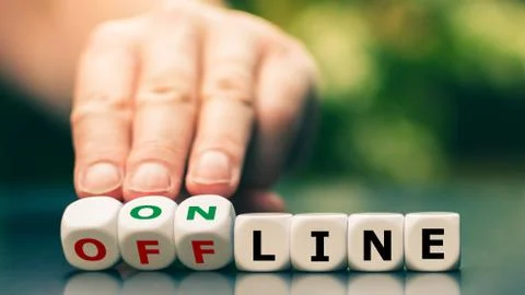 Hand turns dice and changes the expression "offline" to "online". Stock Photos