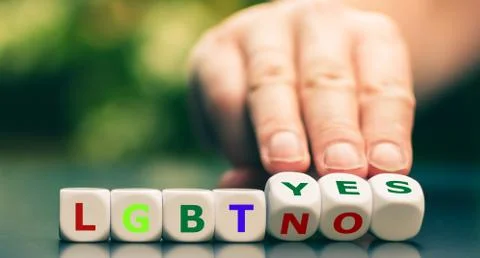 Hand turns dice and changes the expression "LGBT no" to "LGBT yes". Stock Photos