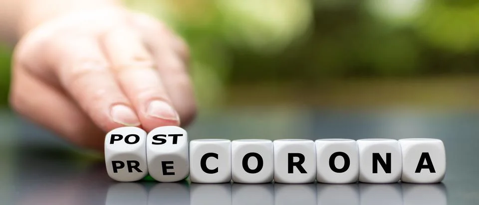Hand turns dice and changes the expression "pre corona" to "post corona". Stock Photos