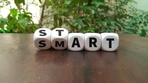 Hand turns dice and changes the word start to smart Foto stock