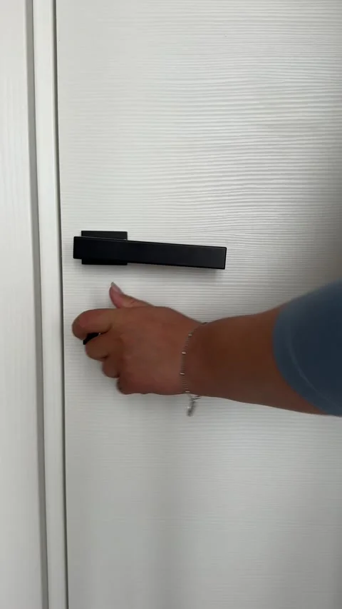 Hand turns a key to lock or unlock a white wooden interior door. Stock-Footage 343676684