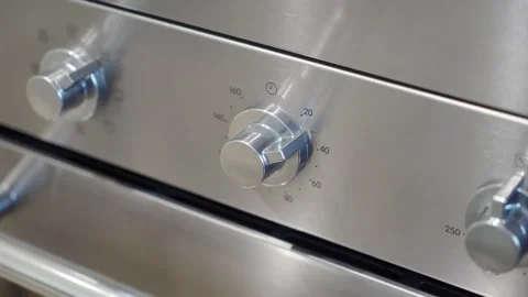 A hand turns the metal timer knob on a stainless steel oven. Stock Footage 320889978