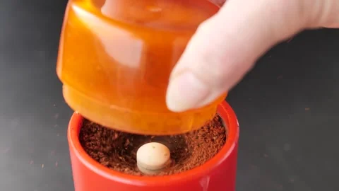 A hand turns an orange manual grinder while coffee grounds. Stock Footage 337352279