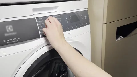 A hand turns the program selector on a washing machine to choose the desired  Video stock 323160931
