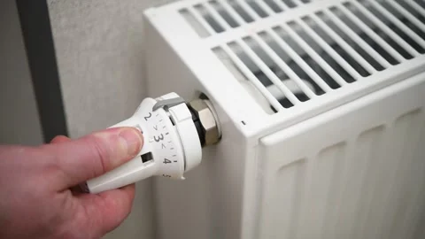 A hand turns a radiator valve to regulate the room temperature in winter. Stock Footage 300080987