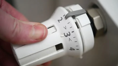 A hand turns a radiator valve to regulate the room temperature in winter. Video stock 300081261