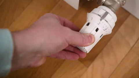 A hand turns a radiator valve to regulate the room temperature in winter. Stock Footage 308066286