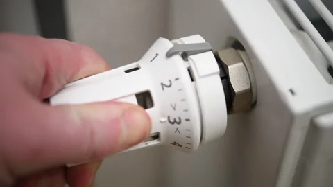A hand turns the radiator valve, regulating the temperature in a cozy room. Stock Footage 304897192