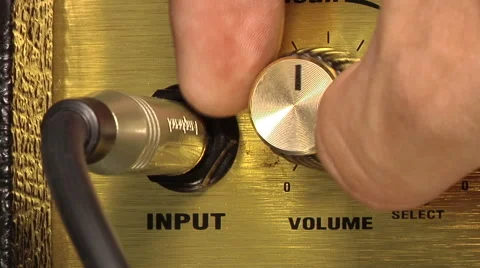 The hand turns the volume knob on the guitar amp Stock Footage