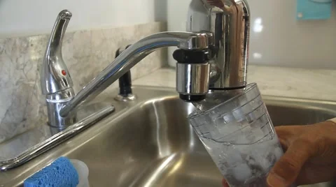Hand turns up water filter and pour into glass, turns it off Stock Footage 45525059