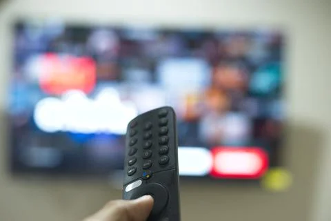Hand with TV remote control, switching TV series from streaming service pla.. Stock Photos