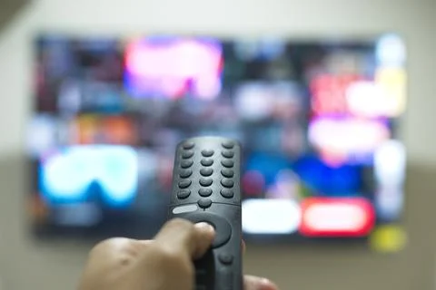 Hand with TV remote control, switching TV series from streaming service pla.. Stock Photos