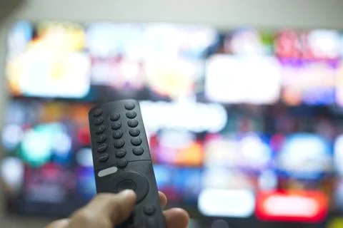 Hand with TV remote control, switching TV series from streaming service pla.. Stock Photos