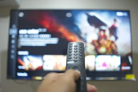 Hand with TV remote control, switching TV series from streaming service pla.. Stock-Fotos
