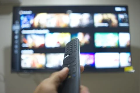 Hand with TV remote control, switching TV series from streaming service pla.. Stock Photos