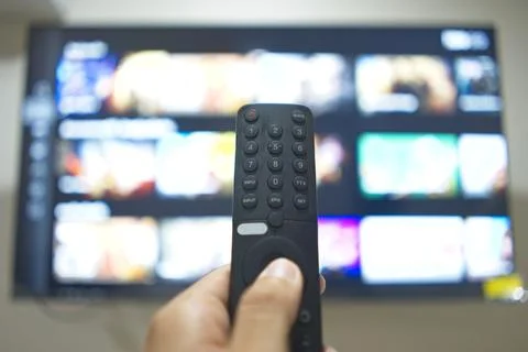 Hand with TV remote control, switching TV series from streaming service pla.. Stock Photos