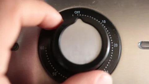 A hand twist a button for controling time in a household item Stock-Footage 148056172