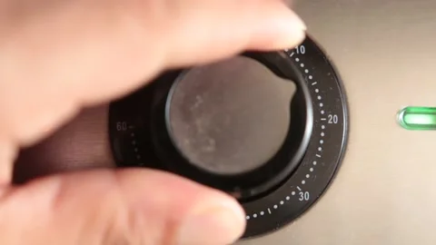 A hand twist a button for controling time in a household item Stock Footage 148056476