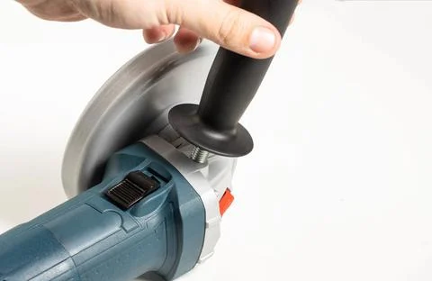 The hand twists the extra handle into the angle grinder for a comfortable grip Stock Photos