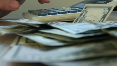 Hand typing on a calculator and dollar banknotes. Savings and home finances. Stock Footage 88346431