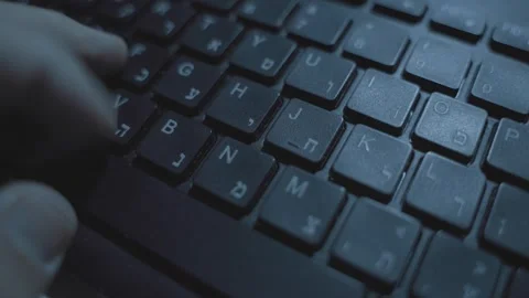 Hand typing on computer keyboard with Hebrew letters in dark office desk Видео 331216104