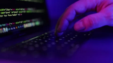 Hand typing on keyboard with coding on screen in a dark room. Stock Footage 337991549