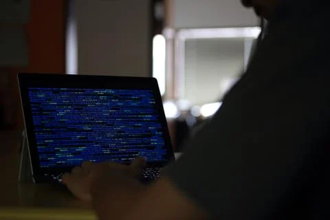 Hand typing on Laptop computer Keyboard side view. screen displaying blue dar Foto stock