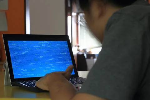 Hand typing on Laptop computer Keyboard side view. screen displaying blue dar Foto stock