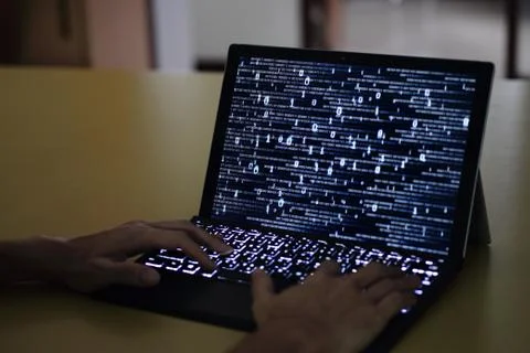 Hand typing on Laptop computer Keyboard side view. screen displaying blue dar Stockfoto's