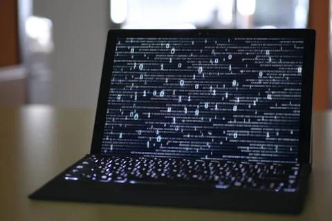 Hand typing on Laptop computer Keyboard side view. screen displaying blue dar 스톡 사진