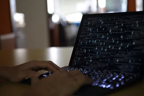 Hand typing on Laptop computer Keyboard side view. screen displaying blue dar Foto stock