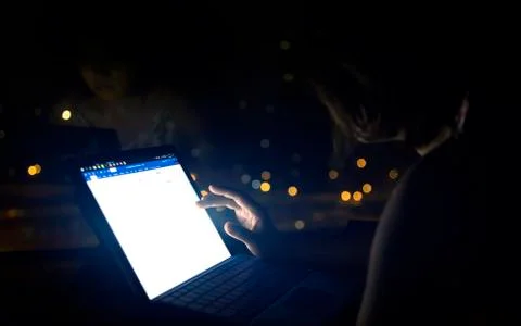 Hand typing notebook working on screen at night Фото