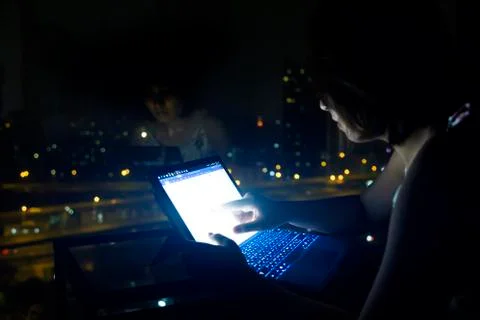 Hand typing notebook working on screen at night 写真素材