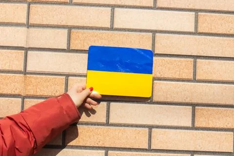 A hand with Ukrainian flag on a brick wall background Foto stock
